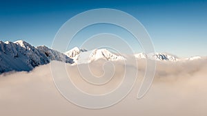 Mountain tops in winter covered in snow with bright sun and blue