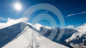 Mountain tops in winter covered in snow with bright sun and blue