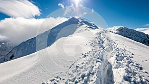 Mountain tops in winter covered in snow with bright sun and blue