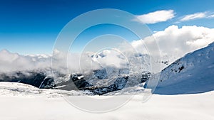 Mountain tops in winter covered in snow with bright sun and blue