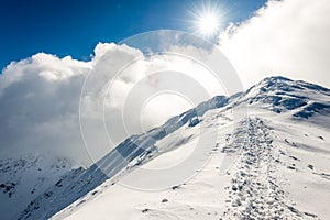 Mountain tops in winter covered in snow with bright sun and blue