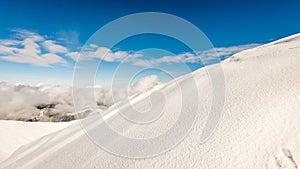 Mountain tops in winter covered in snow with bright sun and blue