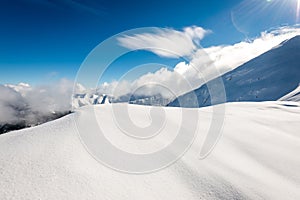 Mountain tops in winter covered in snow with bright sun and blue