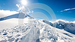 Mountain tops in winter covered in snow with bright sun and blue