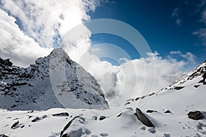 Mountain tops in winter covered in snow with bright sun and blue