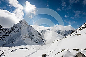 Mountain tops in winter covered in snow with bright sun and blue