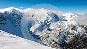 Mountain tops in winter covered in snow with bright sun and blue