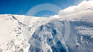 Mountain tops in winter covered in snow with bright sun and blue