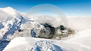 Mountain tops in winter covered in snow with bright sun and blue