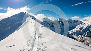 Mountain tops in winter covered in snow with bright sun and blue