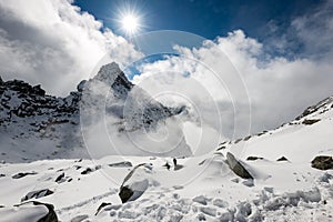 Mountain tops in winter covered in snow with bright sun and blue