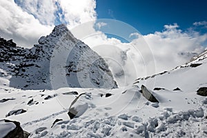 Mountain tops in winter covered in snow with bright sun and blue