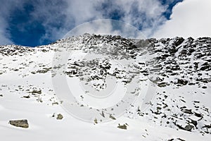 Mountain tops in winter covered in snow with bright sun and blue