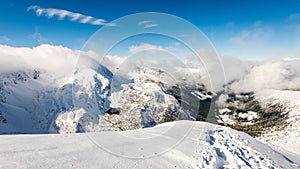Mountain tops in winter covered in snow with bright sun and blue