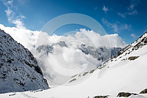 Mountain tops in winter covered in snow with bright sun and blue