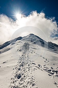 Mountain tops in winter covered in snow with bright sun and blue