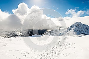 Mountain tops in winter covered in snow with bright sun and blue