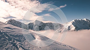 Mountain tops in winter covered in snow with bright sun and blue