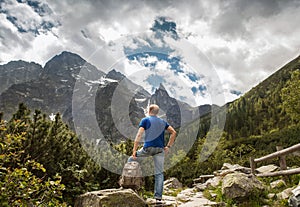 Mountain traveler looks on wild rocks