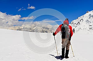 Mountain trekker looking at high winter Himalayas mountains