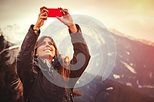 Mountain vacation. Happy woman taking a picture with a cell phone.