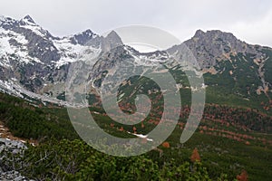 Horské údolie s jesennými červenými farbami a horským hrebeňom pokrytým prvým snehom v pozadí. NP Vysoké Tatry, Slovensko, Tatry,