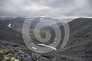 Mountain valley with mosses and rocks covered with lichens. Cloudy sky before storm. Khibiny mountains above the Arctic