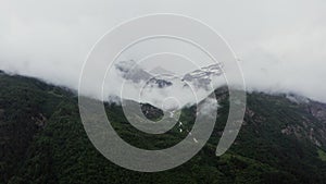 A mountain valley with river in lowland at the foot of rocks with snow