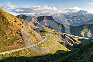 Mountain valley shined with the sunset sun with the road on an abrupt slope