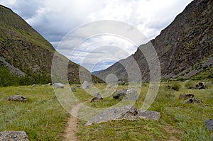 Mountain valley and a trail on a cloudy summer day.