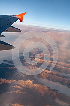 Mountain view in the clouds from the wing of an airplane on a summer day