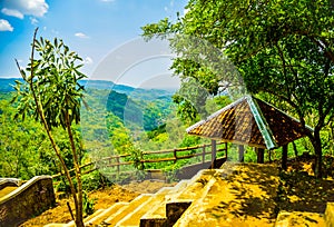 Mountain view of a rest hut with lush green forest and yellow river in East Asia