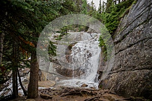 A mountain waterfall of coniferous forest and the slopes of the Rocky Mountains. Tourism concept, eco recreation, Alberta, Canada