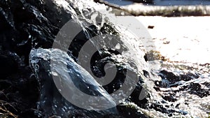 Mountain waterfall, creek, river. Water splashes over stones in sunlight