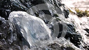 Mountain waterfall, creek, river. Water splashes over stones in sunlight