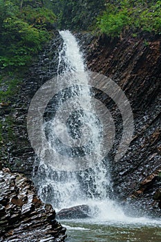 Mountain waterfall, large water flow of mountain waterfall, mountain river near the rock. Huk Waterfall, Ukrainian