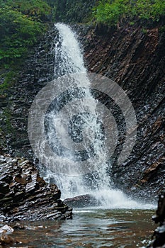 Mountain waterfall, large water flow of mountain waterfall, mountain river near the rock. Huk Waterfall, Ukrainian