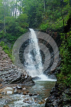 Mountain waterfall, large water flow of mountain waterfall, mountain river near the rock. Huk Waterfall, Ukrainian