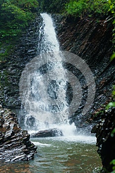 Mountain waterfall, large water flow of mountain waterfall, mountain river near the rock. Huk Waterfall, Ukrainian