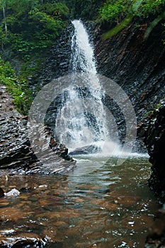 Mountain waterfall, large water flow of mountain waterfall, mountain river near the rock. Huk Waterfall, Ukrainian