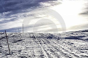 The mountain way for driving of snow mobiles, marked by red orange sticks, Scandinavian Mountains, cold sunny winter day, typical
