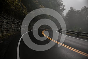 Mountain wet asphalt road curve at fog rainy day.