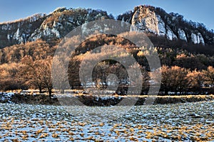 Mountain winter landscape with a rock in the background at sunset.