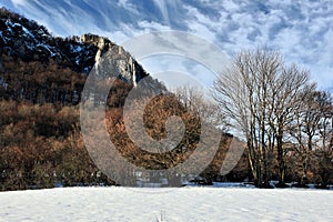 Mountain winter landscape with rock and trees. Beautiful cluster of white clouds