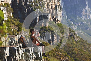 Mountain, woman and hiking for fitness with binoculars on cliff to relax for explore, journey and trekking as backpack