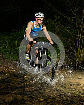 Mountainbiker driving through a streambed