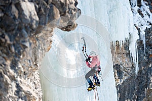 Mountaineer ascends the vertical icefall with ice picks photo