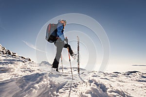 Mountaineer backcountry ski walking in the mountains. Ski touring in high alpine landscape. Adventure winter extreme sport. Sunny