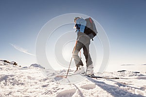 Mountaineer backcountry ski walking in the mountains. Ski touring in high alpine landscape. Adventure winter extreme sport. Sunny