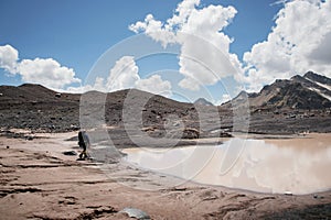 A mountaineer with a backpack walks in crampons walking along a dusty glacier with sidewalks in the hands between cracks